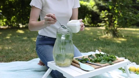 Preparing refreshing herbal drink in a sunny garden setting Stock Footage 297370260