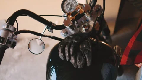 Preparing to ride a motorcycle in a garage setting while wearing leather gloves Stock Footage 313848479