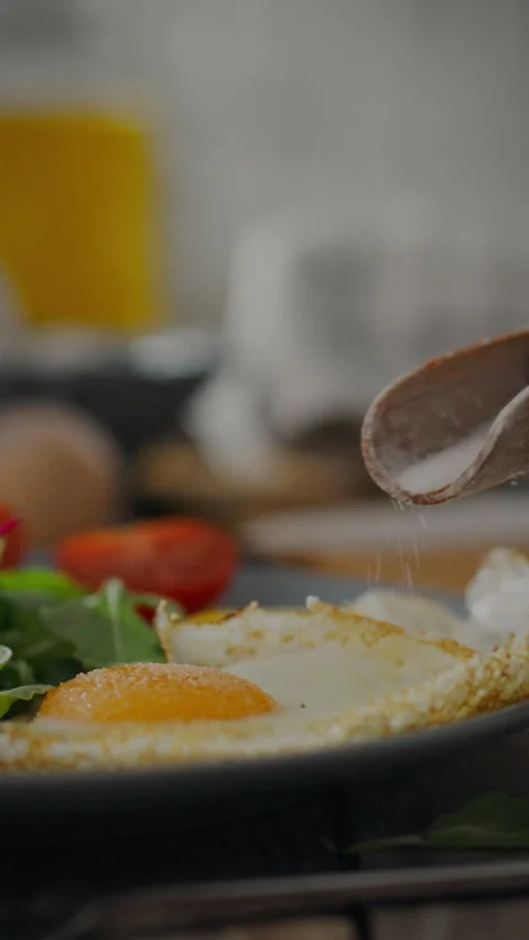 Preparing a savory breakfast with seasoned eggs and fresh vegetables at a ho Stock Footage 331720672