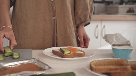 Preparing a simple meal with cucumber and salmon on toast in the kitchen Stock Footage 340193625