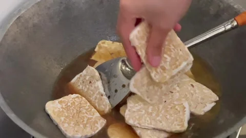 Preparing sliced raw tempeh in a traditional marinade sauce for cooking bacem Stock Footage 327242201