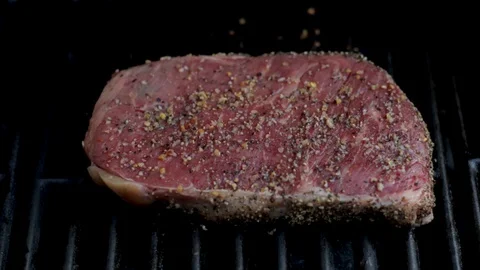 Preparing steak dinner raw fillet mignon steak seasoned and grilling on BBQ clos Stock Footage 130065781