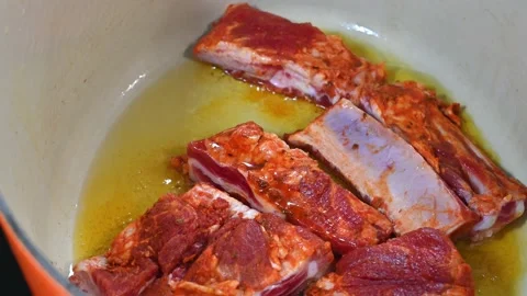 Preparing a stew of roasted ribs, starting to fry them in oil Stock Footage 219720373