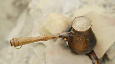 Preparing turkish coffee in a copper cezve over a fire. Boiling coffee Stockbeeldmateriaal 172573510