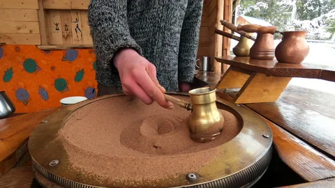 Preparing Turkish coffee in a copper cezve on hot sand is an old Turkish way of Stock Footage 175886990