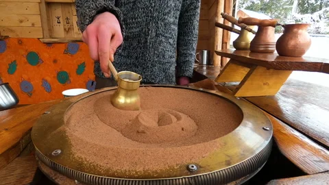 Preparing Turkish coffee in a copper cezve on hot sand is an old Turkish way of Stock Footage 176549602