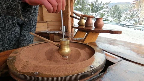 Preparing Turkish coffee in a copper cezve on hot sand is an old Turkish way of Stock Footage 177997993