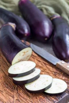Preparing vegetable dish. Eggplant and eggplant slices on wooden cutting boar 스톡 사진
