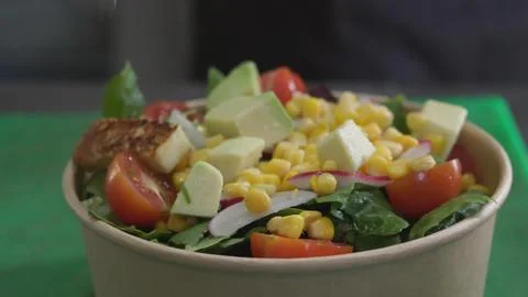 Preparing vegetable salad with grilled cheese in eco-friendly paper bowl Stock Photos