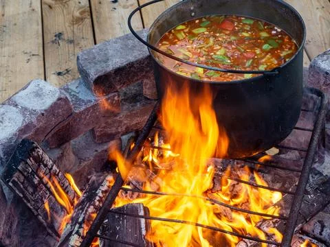 Preparing vegetable soup on campfire using traditional cooking method Stock Photos