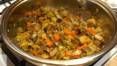 Preparing a vegetable stew. The cook stirs the vegetable ragout with a spoon Stock-Footage 321195035