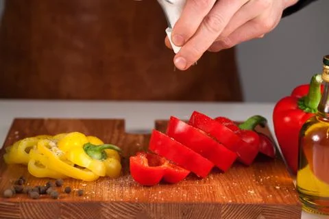 Preparing vegetables using salt-shaker. Chef holding salt-shaker above sliced Stock Photos