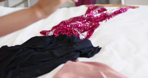 Prepping for evening, hands are smoothing pink sequined dress and unfolding pale Stock Footage 344645055