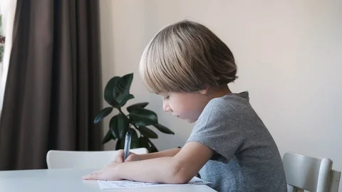 Preschool boy, child, sitting at the table at home and drawing or doing homework Stock Footage 124110168
