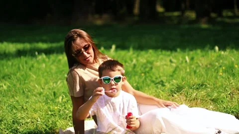 Preschool boy having fun blowing soap bubbles in park. Game of blowing bubble Stock Footage 320252430