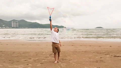 Preschool boy playing with bubbles on beach. Stock Footage 266780585