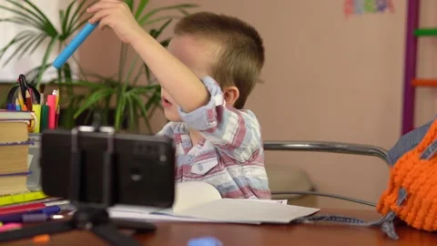 A preschool boy pulls out and removes the cap from a blue felt-tip pen as he 스톡 동영상 162370329