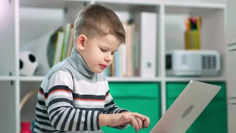A preschool boy is studying something on his laptop at home Stock Footage 102819229