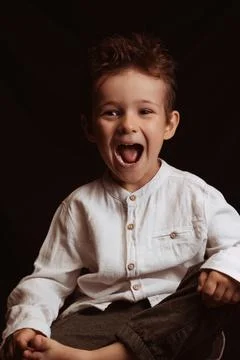 Preschool child boy screams while sitting on chair Stock Photos
