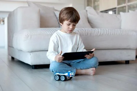 Preschool child uses distant controller on tablet pc to drive self-made robot Stock Photos