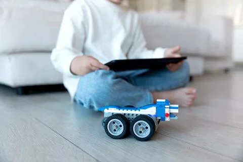 Preschool child uses distant controller on tablet pc to drive self-made robot Stock Photos