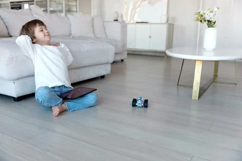 Preschool child uses distant controller on tablet pc to drive self-made robot Stock Photos