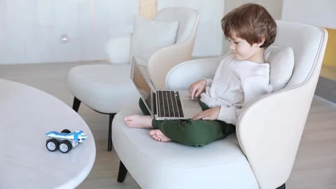 A preschool kid uses lap top, and controls the robot made of bricks Stock Footage 253975372