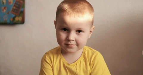 Preschool sit in front of camera, looks into lens, embarrassed, smiles, emotions Stock Footage 126307806
