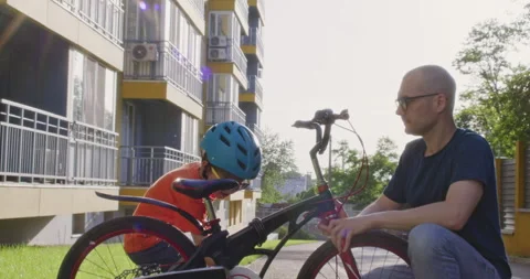 Preschooler boy cheerfully tests performance of bicycle with dad Stockbeeldmateriaal 285492378