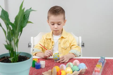 Preschooler boy focused on drawing an Easter pattern while sitting at the tab Stock-Fotos