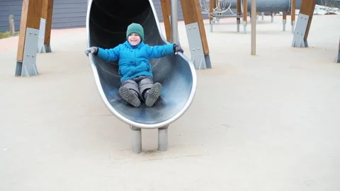 A preschooler boy rolled down an enclosed tube slide on the playground in the Stock Footage 194858779