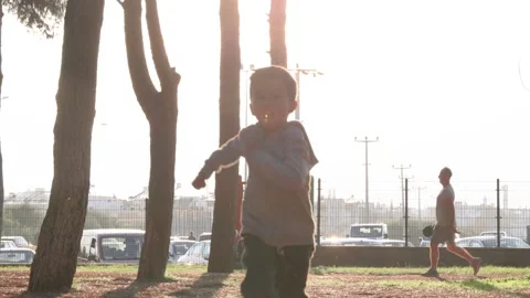 Preschooler boy running towards camera in the park at sunset time. Slow-motion Stock Footage 244828641