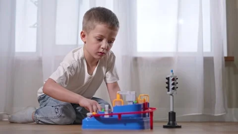 Preschooler boy sits on floor playing. Curious child moves toy elements. Toddler 库存影片 318445897