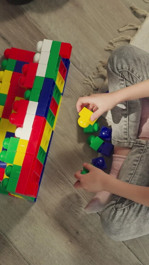 Preschooler builds structure from plastic blocks on floor Video stock 285861644
