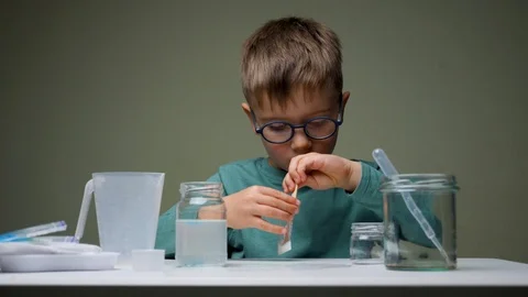 Preschooler doing experiment. Young scientist in glasses mixing up licquid for Stock Footage 119720371