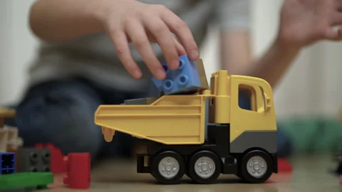 Preschooler plays constructor and builds a car and rolls it with his hand on the Stock Footage 219496483