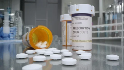 Prescription drug cost bottle with pills out in medical lab Stock Footage