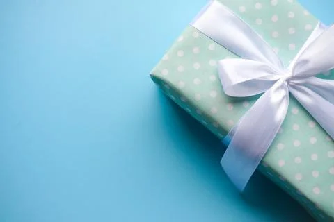 Present on blue background.Gift with white ribbon.Space for text. Stock Photos