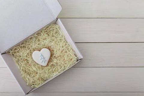 Present box and gingerbread cookie. Heart shape. Sweets on white wooden table Stock Photos