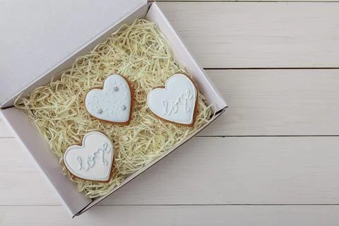 Present box and gingerbread cookie. Hearts shapes. Sweets on white table Stock Photos