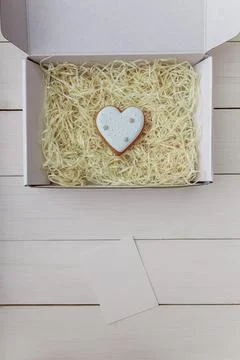 Present box and gingerbread cookie. Heart shape. Sweets on white wooden table Stock Photos
