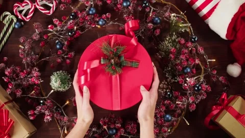 Present box in christmas wreath top view. Hands putting red gift on table close Stock Footage 163611068