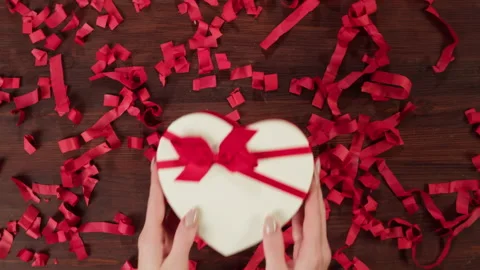 Present box on confetti background. Hands putting red gift on table close-up Stock Footage 163682087