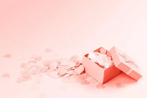 Present box on pink background with multicolored confetti. Stock Photos