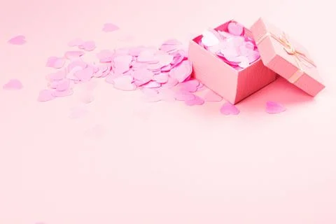 Present box on pink background with multicolored confetti. Stock Photos
