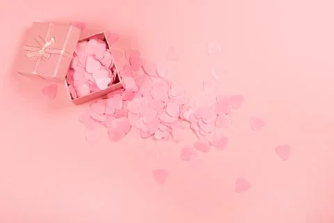 Present box on pink background with multicolored confetti. Stock Photos