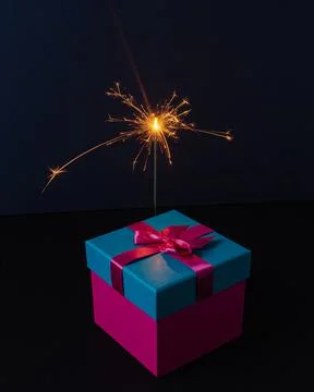 A present box with a sparkler on dark background Stock Photos