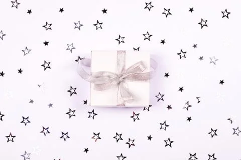 Present box on white background with silver star confetti . Stock Photos