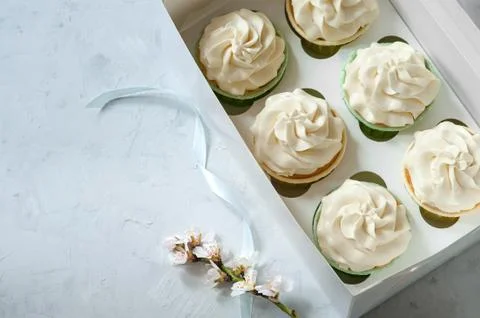 Present concept. Fresh white flowers and gift box with cupcakes on wooden table Stock Photos