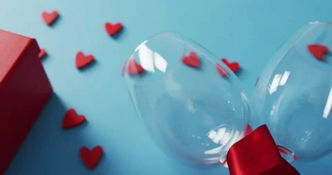 Present, hearts and wine glasses on blue background at valentine's day Stock Footage 336056845